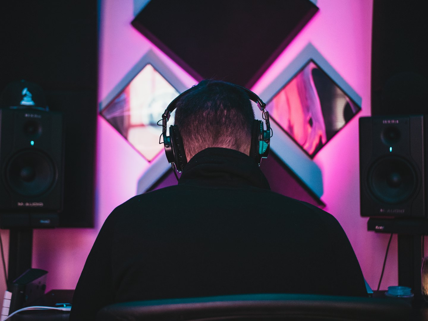 Person with headphones working at a desk in a neon-lit studio.